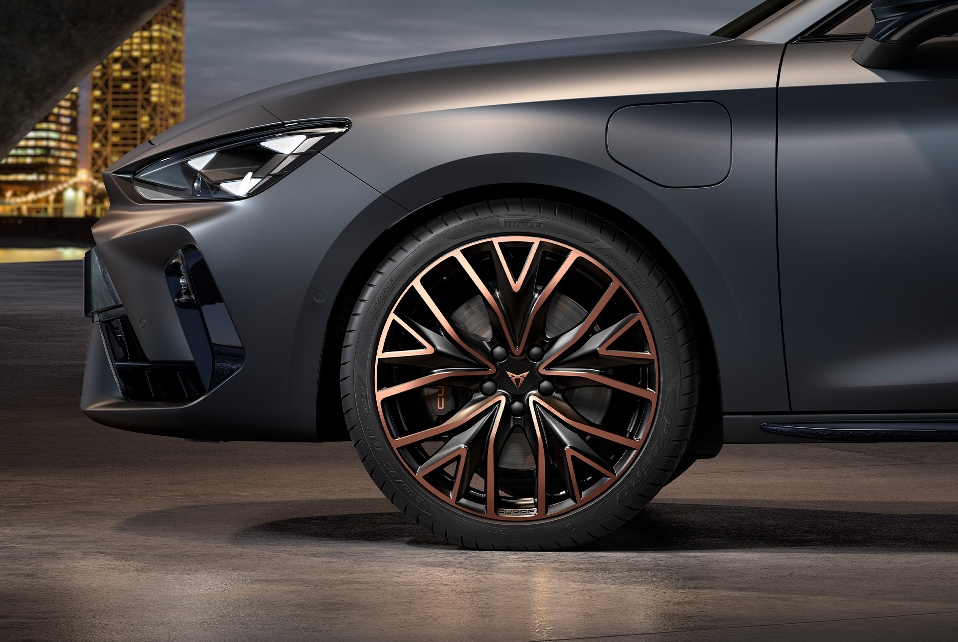 front side view of left mistral copper forged wheels in copper and black for the cupra leon Sportstourer, tyres, signature headlights and grey body