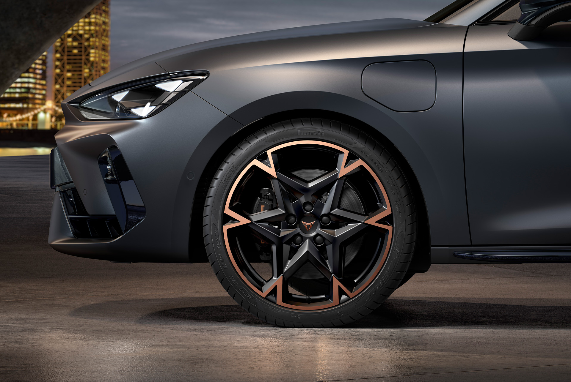front side view of left machined alloy wheel in black and copper for the cupra leon Sportstourer, tyres, signature headlights and grey body