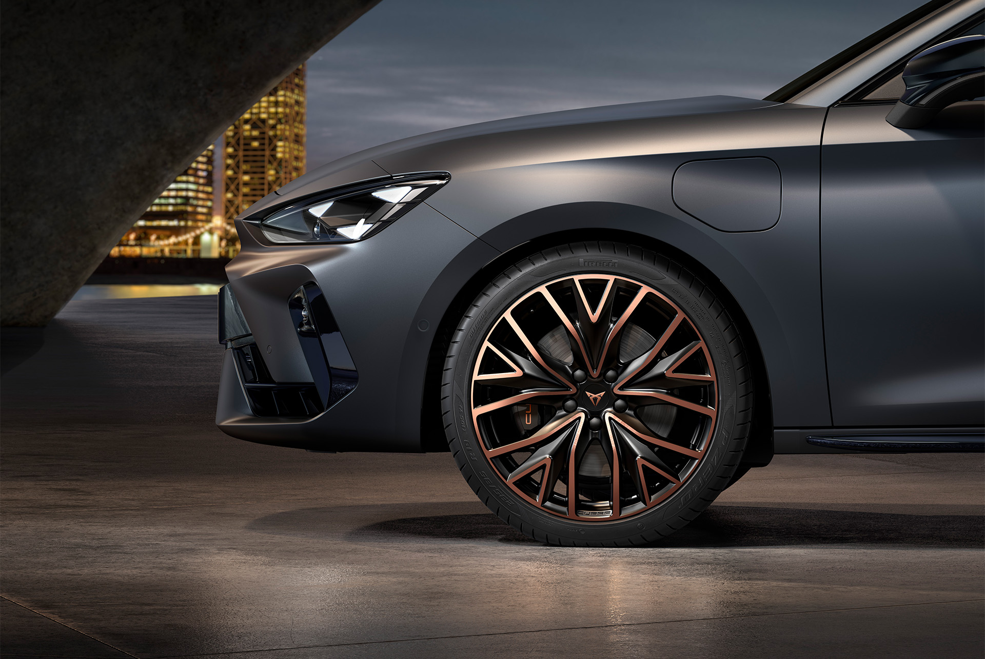 front side view of left mistral copper forged wheels in copper and black for the Cupra Leon, tyres, signature headlights and grey body.