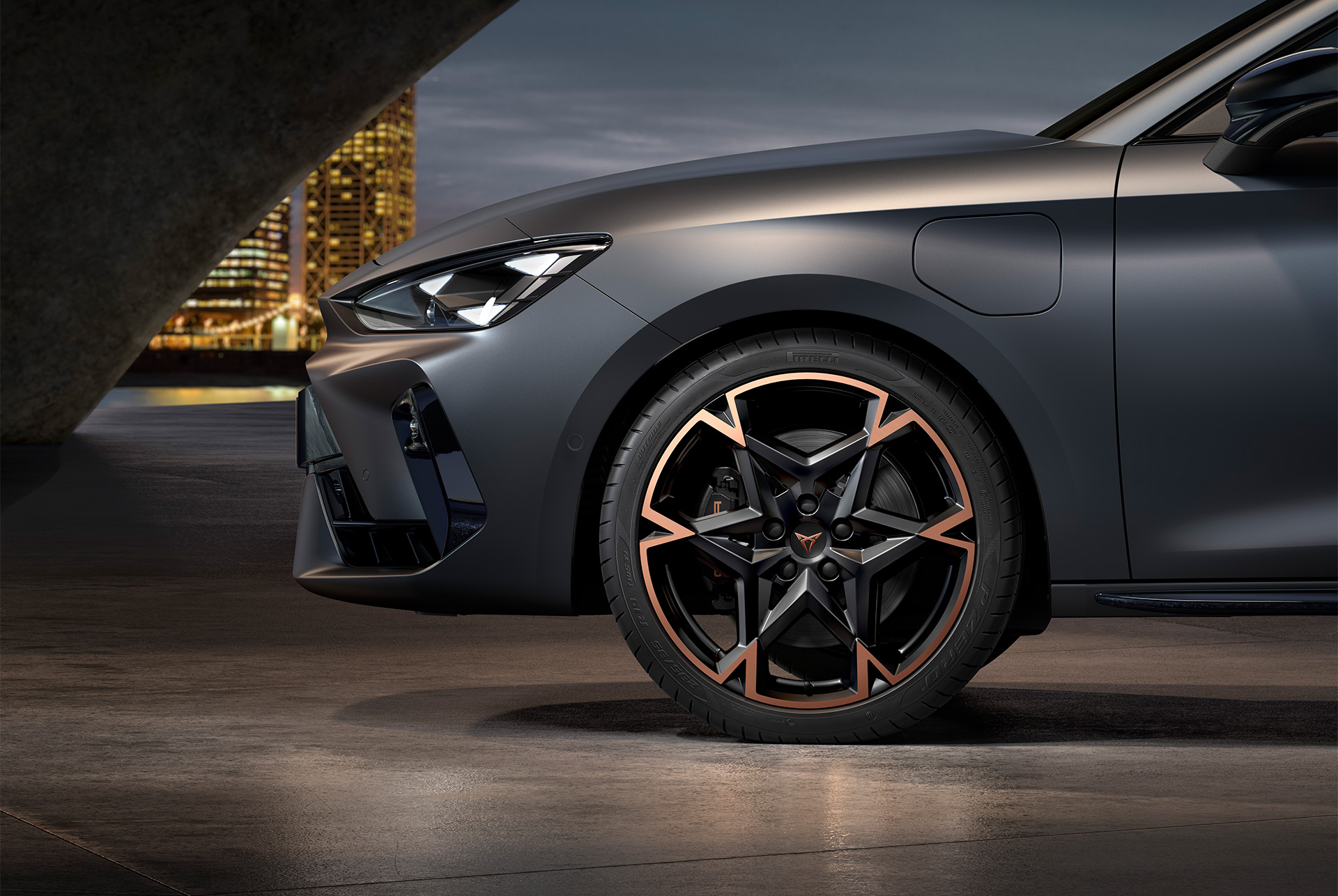front side view of left machined alloy wheel in black and copper for the Cupra Leon, tyres, signature headlights and grey matt body.