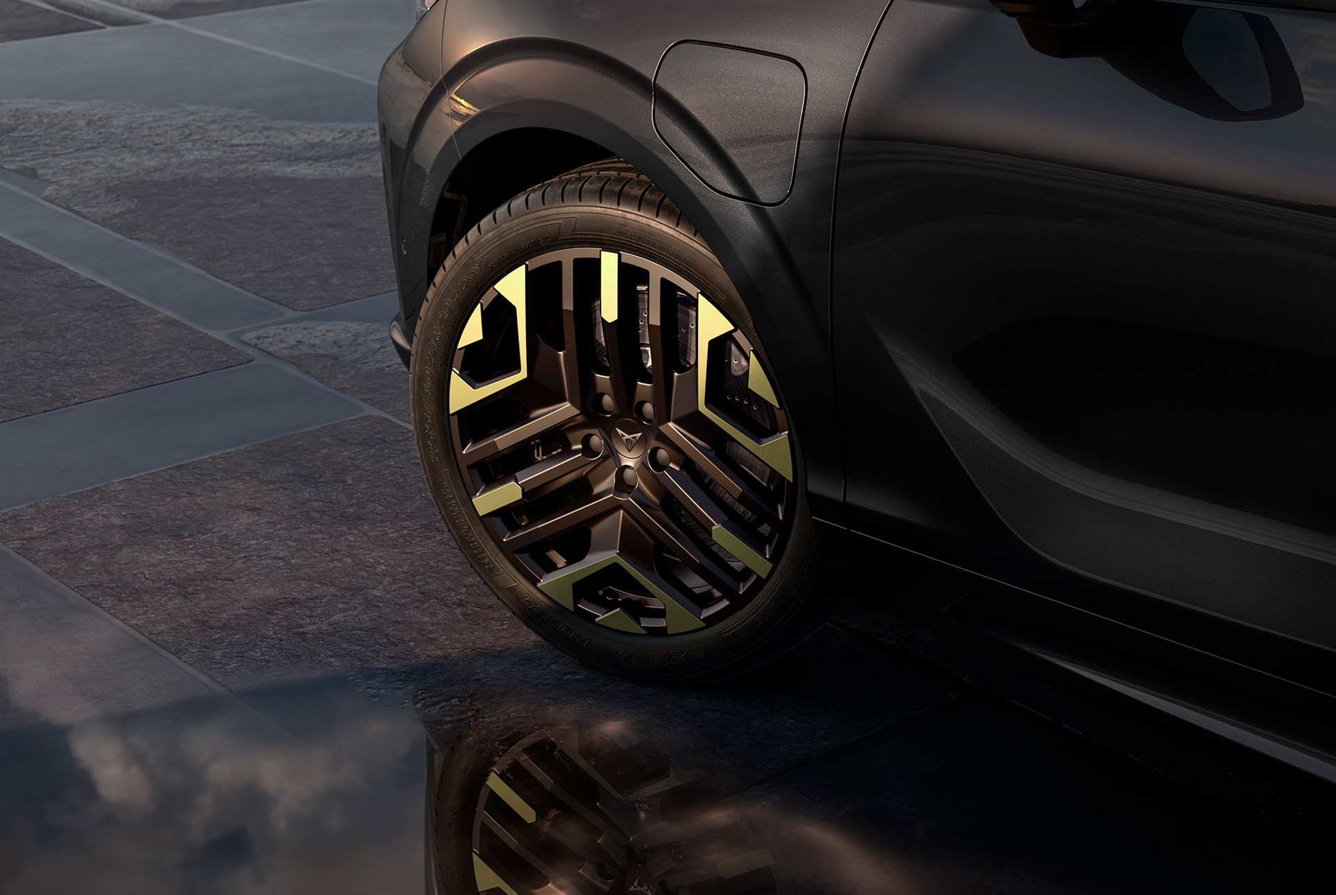 Left 20-inch sulphur alloy wheel on the cupra terramar from the new tribe edition, against a tiled, dark pavement to complement the glossy dark body