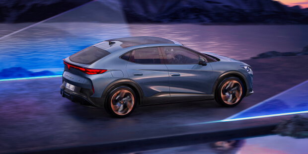 Electric CUPRA Tavascan driving along a scenic coastal road at sunset, with mountain landscape and futuristic light beams, showcasing innovative electric vehicle design.