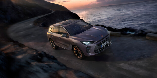 What is regenerative braking shown by CUPRA Terramar VZ plug-in hybrid driving on a coastal road at sunset, front angle view.